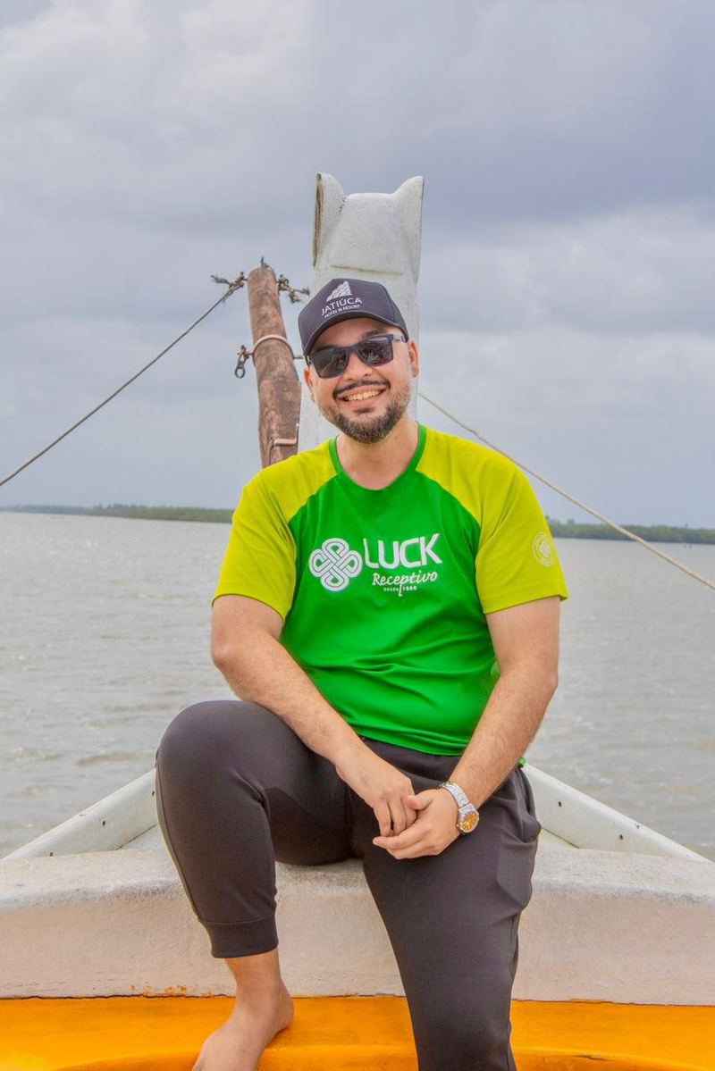 Leo Viana sentado num barco na Foz do Rio São Francisco, com a camisa da Luck Receptivo