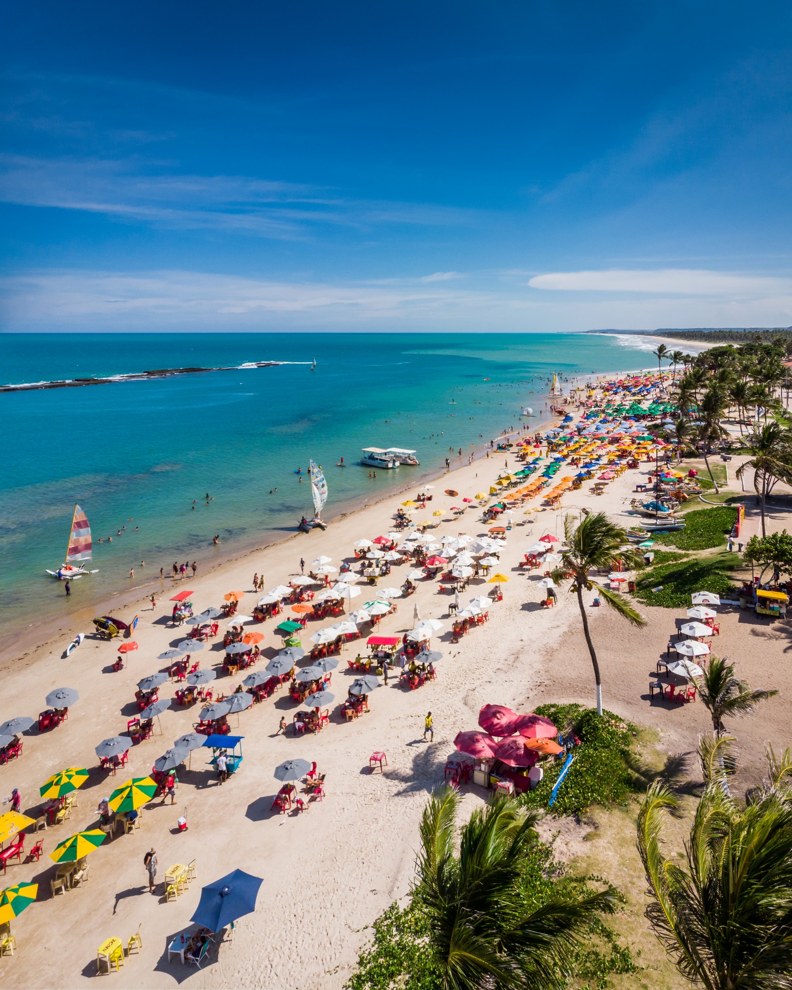 Vista aérea da Praia do Francês com guarda-sóis coloridos e mar turquesa