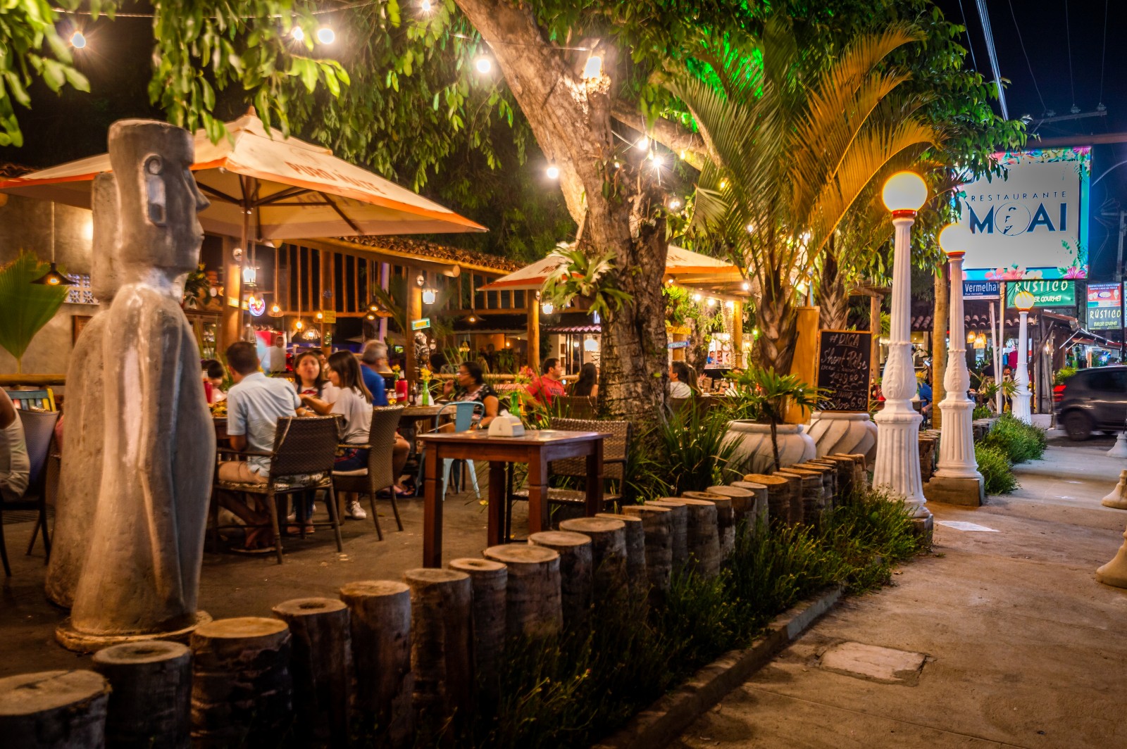 Restaurante Moai com clientes e estátua na Vila do Francês By Night