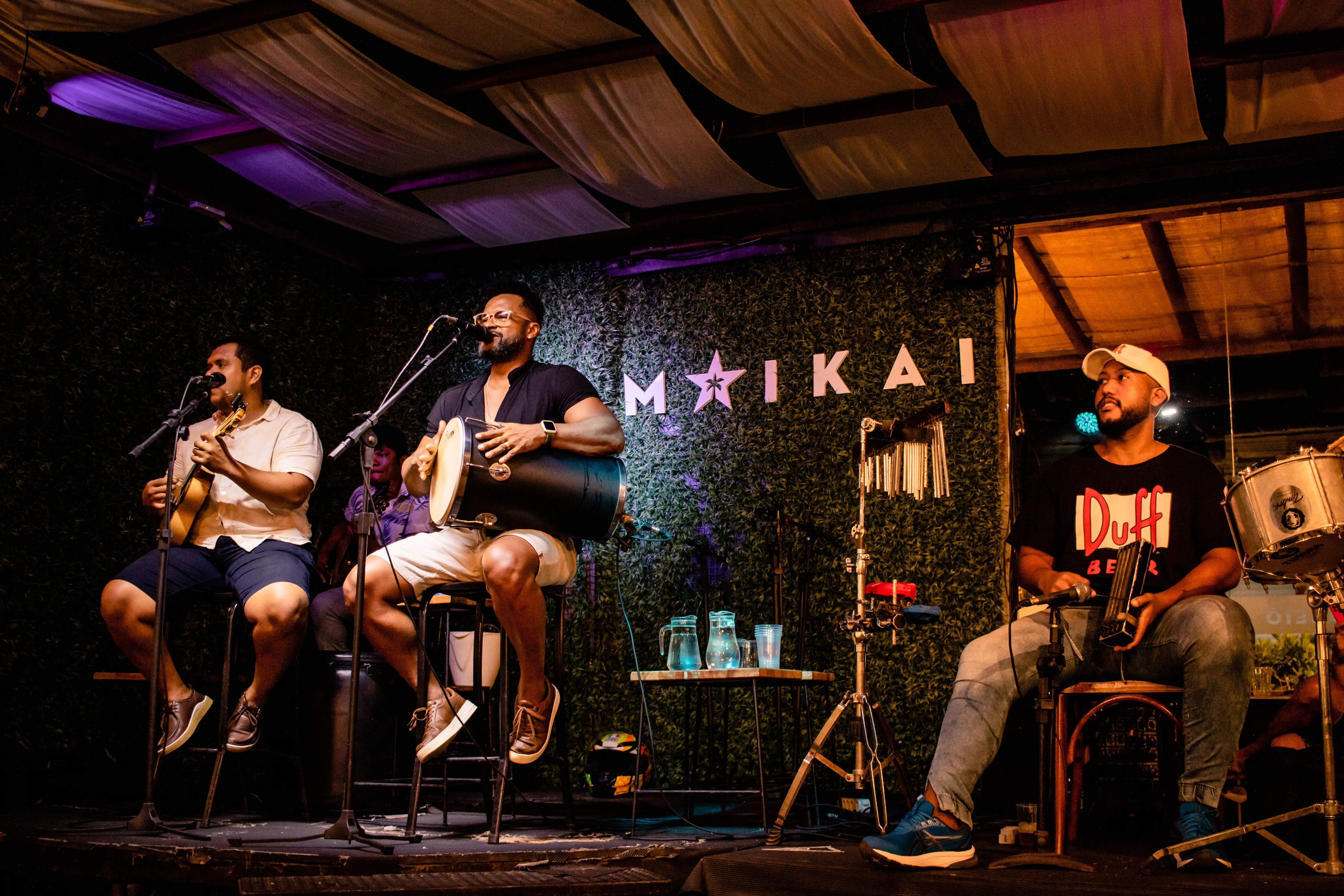 Banda ao vivo no palco do Maikai Show Bar com backdrop iluminado