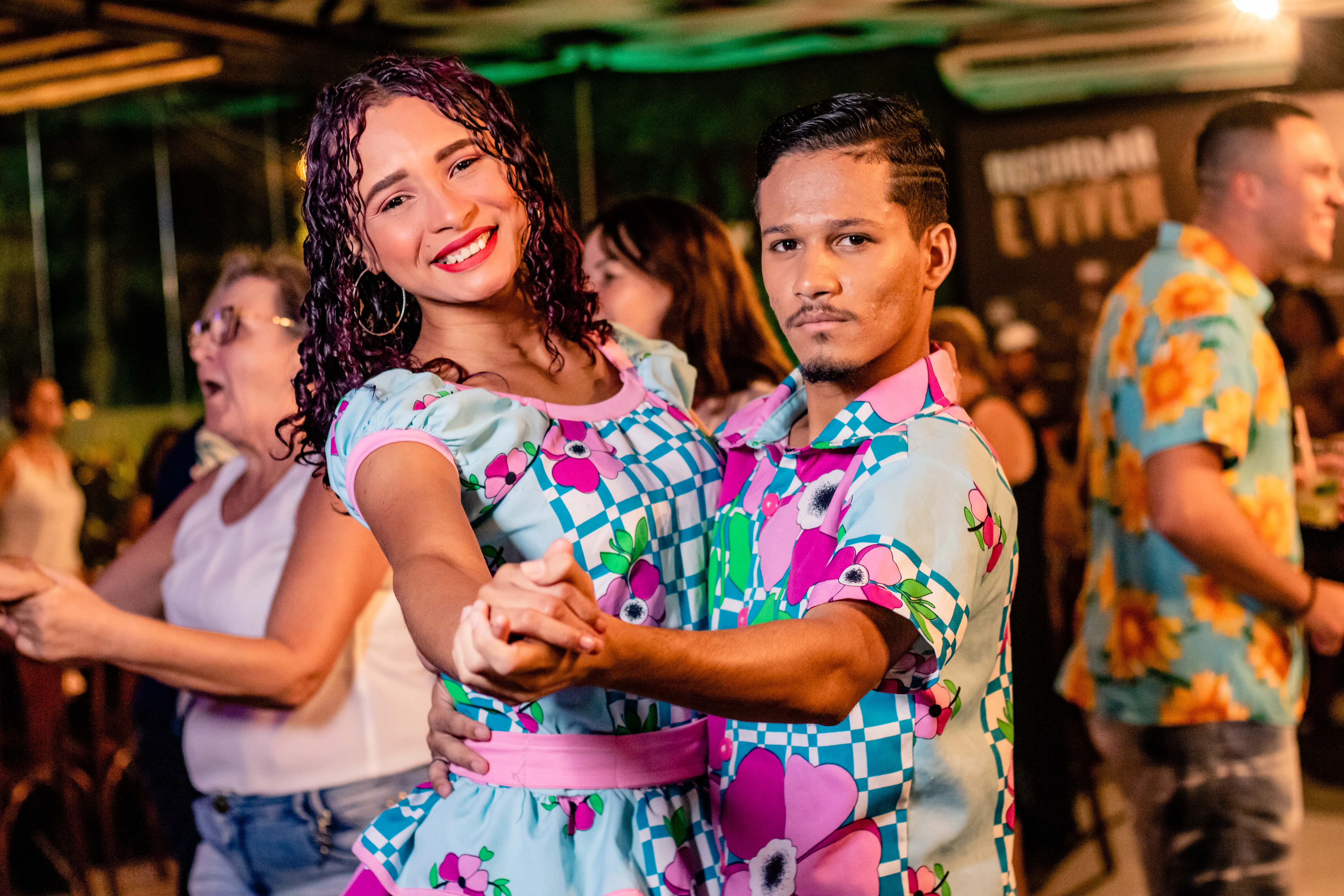 Casal dançando em trajes típicos floridos na Noite do Turista