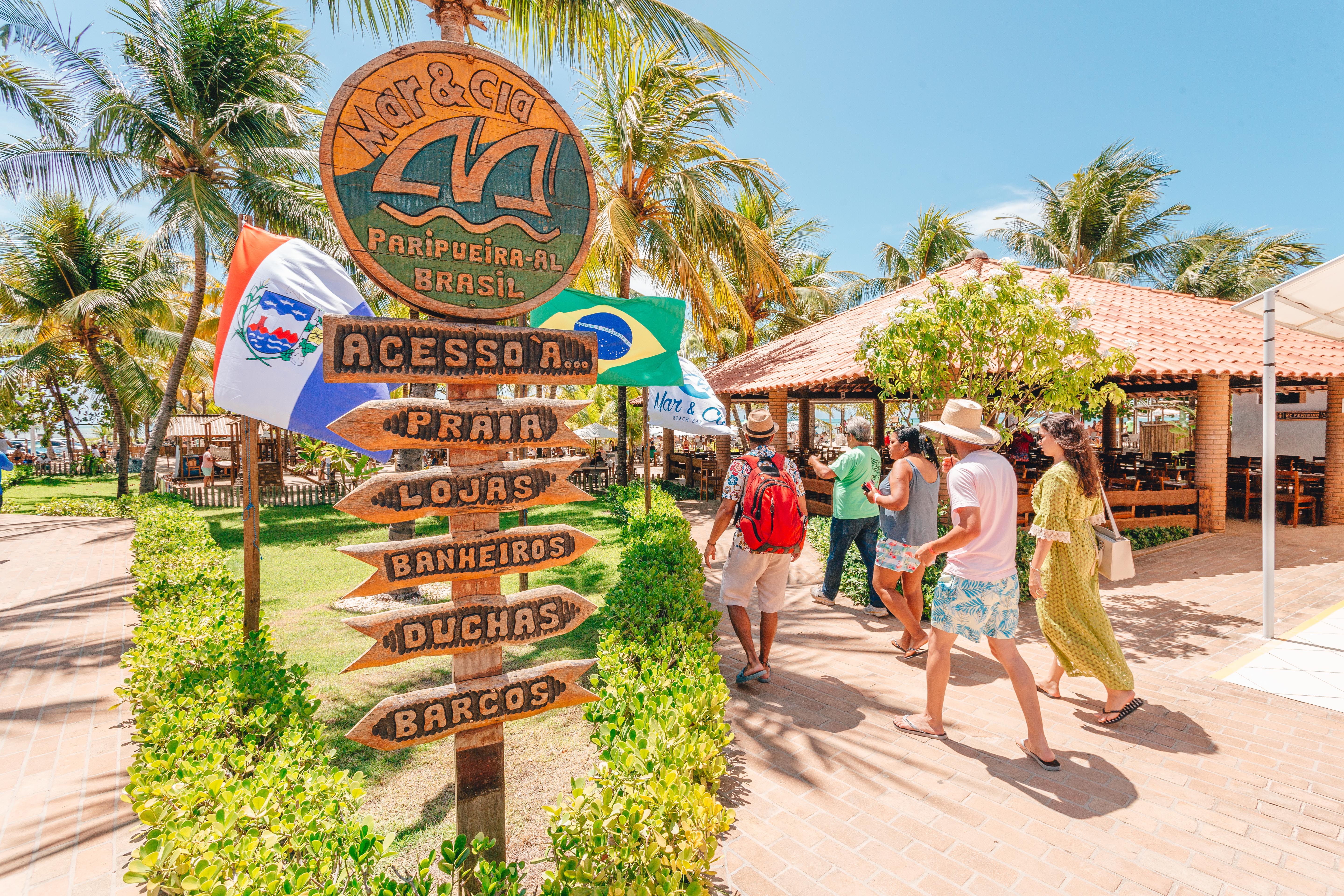 Placa de entrada do Mar & Cia em Paripueira com turistas